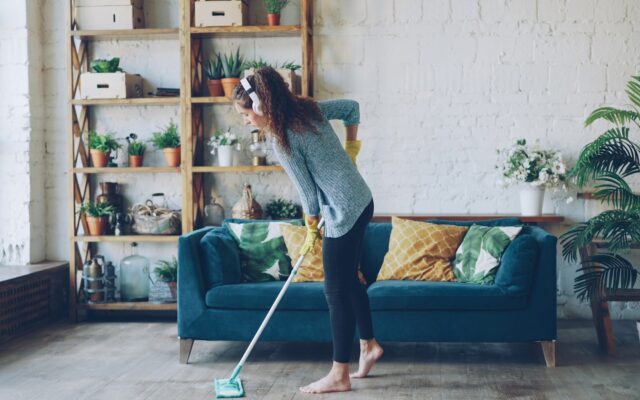 Woman mopping floor while wearing headphones.